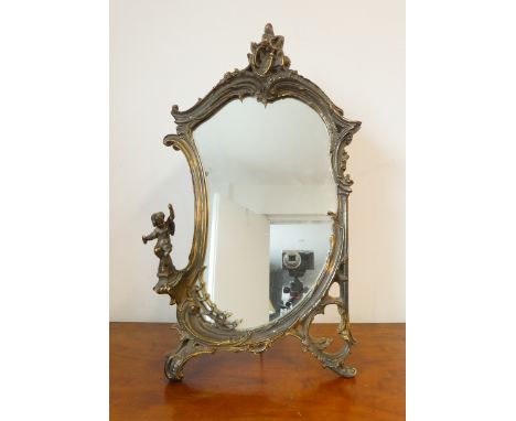 A gilt framed easel-style looking glass in high Rococo style with a seated cherub to the left (58cm high x 34cm widest)