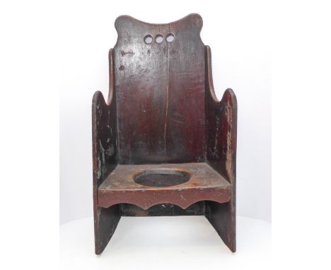 An unusual antique child's painted (on elm) winged commode chair (probably 18th century), three pierced circles to the top ra