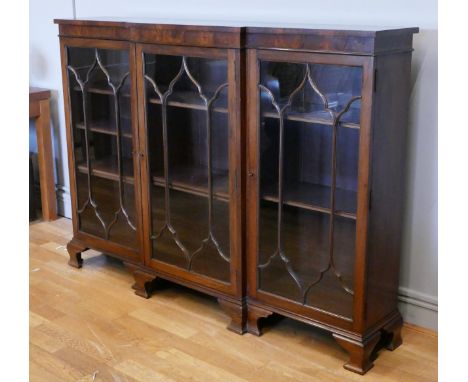 An Edwardian astragal breakfront bookcase, having four glazed doors, enclosed shelving and raised on carved bracket feet. 