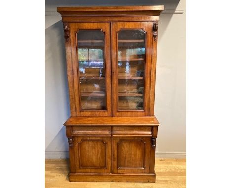 A Victorian mahogany bookcase, having moulded cornice supported by two decorative carved corbels, the glazed doors open to re