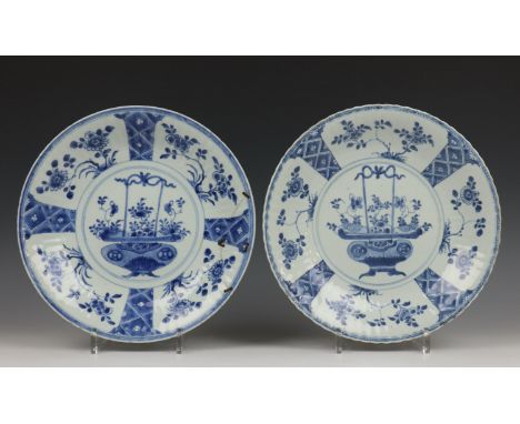   China, paar blauw-wit porseleinen borden, Kangxi, met geplooide rand en decor van bloemenmand (één met krammen).  28,5 cm. 