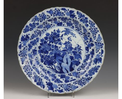   China, blauw-wit porseleinen schotel, Kangxi, met gelobde rand en decor van vakwerk, het plat met rotsformatie met twee pau