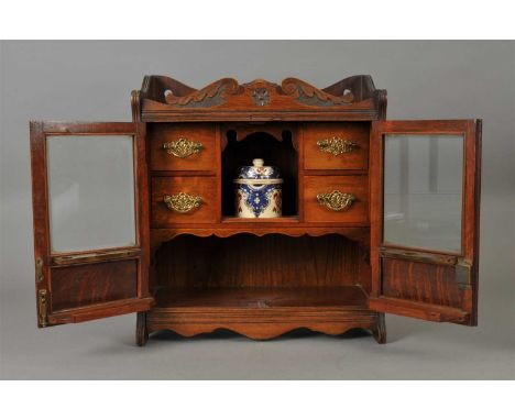 An Edwardian oak smoker's cabinet, the raised bordered top with a broken shallow carved pediment, above a pair of hinged pane