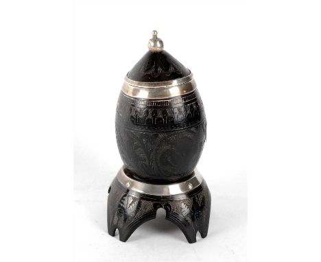 A 19th century Indo-Portugese lidded coconut cup on stand with applied studded white metal mounts, the pointed bowl with a po