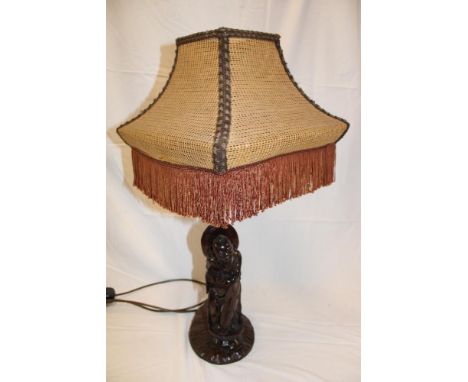 A Chinese carved wood table lamp in the form of a male character with inset wire decoration on rustic base with brass stem an