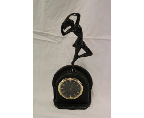 An Art Deco mantel clock with circular dial in painted metal arched case surmounted by a female athlete figure, 12" high