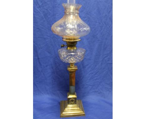 An Edwardian brass oil lamp with cut glass reservoir and square ornamental column supporting a tinted glass shade