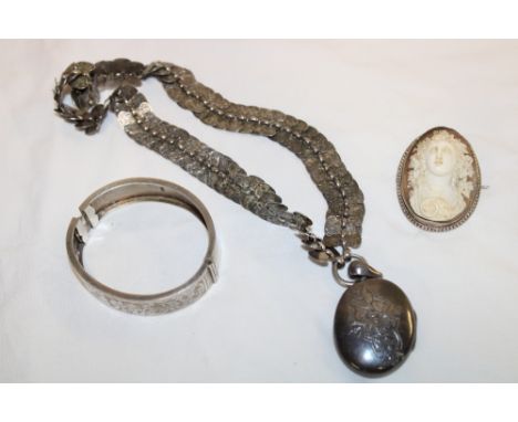 A silver oval locket with engraved decoration and ornate chain, silver mounted cameo brooch and a silver oval bangle (3)