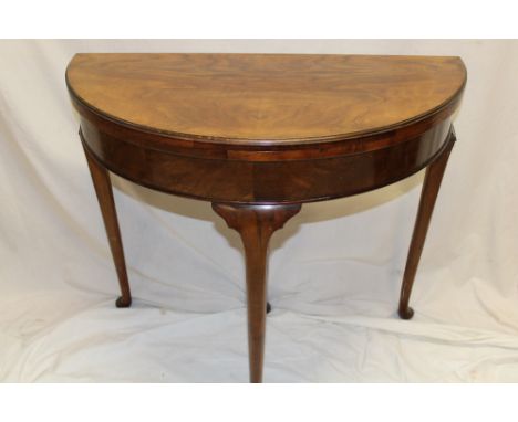 A 1930's figured walnut semi-circular turn-over top card table with baize lined playing surface on cabriole legs