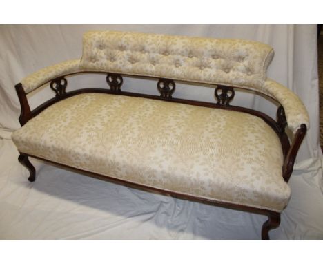 A late Victorian carved mahogany curved three-seat sofa with upholstered seat and buttoned back on scroll shaped legs