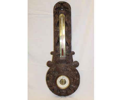 A Chinese-style aneroid barometer with circular dial below thermometer in carved teak case depicting dragon characters