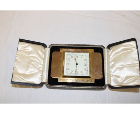 An gilt eight-day travelling clock with presentation text in velvet lined case