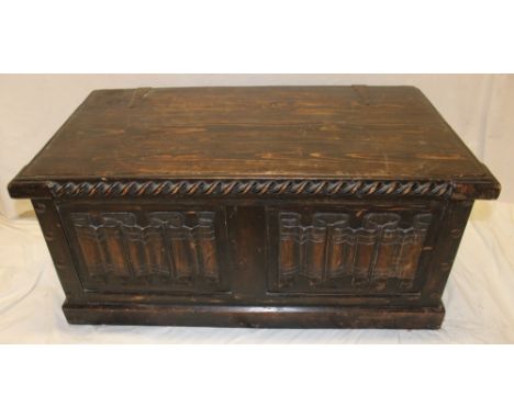 A stained and carved pine rectangular trunk with decorated front and hinged lid
