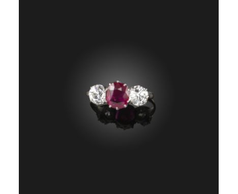 A ruby and diamond three stone ring, the central cushion-shaped ruby set within old circular-cut diamonds claw-set in platinu