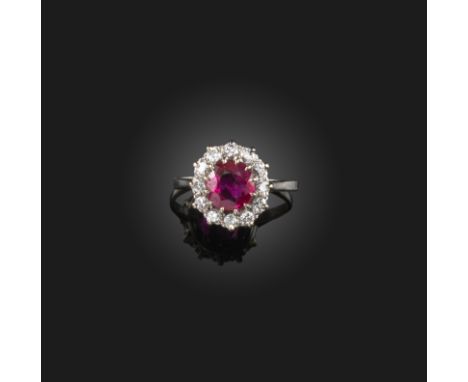 A ruby and diamond cluster ring, mid 20th century, set with an oval ruby weighing approximately 1.25 carats, within a border 