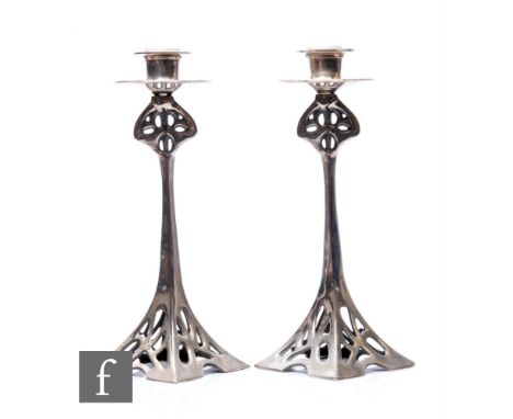 In the manner of WMF - A pair of Art Nouveau silver plated candlesticks, the pierced square section reticulated bases, rising