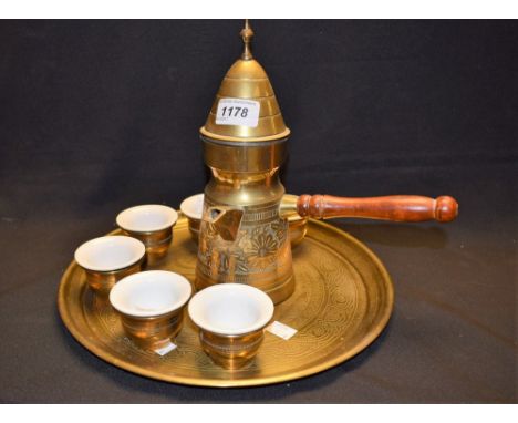 A brass Turkish coffee pot and six beakers with ceramic liners, on a circular brass serving tray