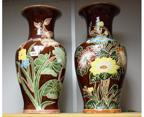 A pair of large ceramic vases, floral decoration on burgundy ground