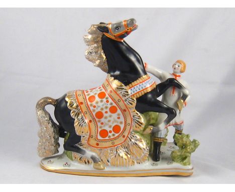 A Russian ceramic group of a caparisoned horse and its handler, green moose head mark for Gardner to base.ht.26cm. 