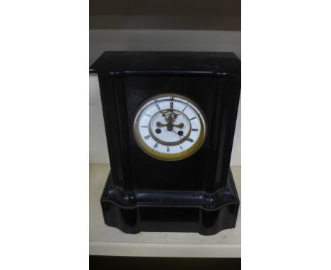 A 19th century French black polished slate mantel clock with circular porcelain dial, Roman numerals with visible escapement 
