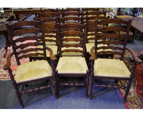 A set of twelve oak ladder back country dining chairs including two carvers, shaped horizontal splats, rush seat, turned stre