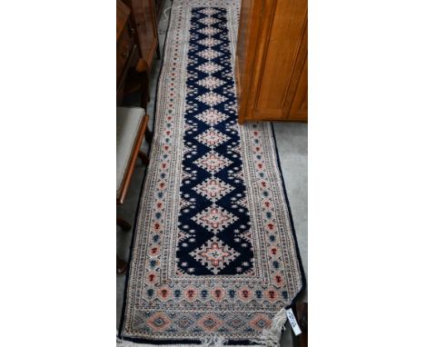 Indo-Persian Turkoman design runner with diamond medallions on a navy blue field framed by the repeating borders, 324 cm x 80