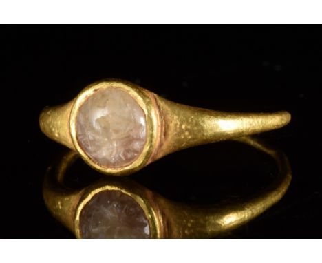 Ca. 100-300 AD. A gold finger ring composed of a slender round hoop expanding to form a circular bezel set with a rock crysta