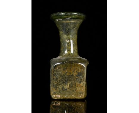 Ca. 1st-3rd century AD. Blown glass flask with a roughly cuboid body and an elongated neck that flares outwards towards the t