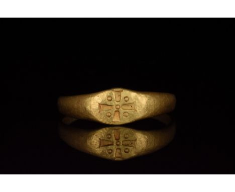 Ca. 1000-1500. A beautiful gold ring with a circular hoop and flattened bezel bearing a punched Greek cross bordered by four 