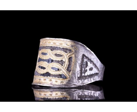 Ca. 900-1100 AD. A silver ring with a D-shaped hoop and flattened, rectangular bezel bearing a gilded interlaced design. Exce