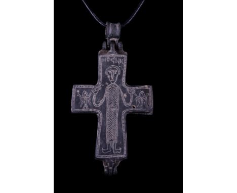 Ca. 800-1000 AD. A reliquary cross pendant cast in two separate pieces and hinged at the top and bottom. The obverse face is 