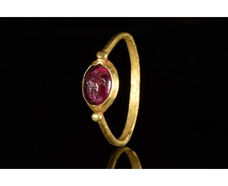 Ca. 100-200 AD. A gold finger ring of a thin hoop with fine granules to each shoulder. The bezel centred by an intaglio depic