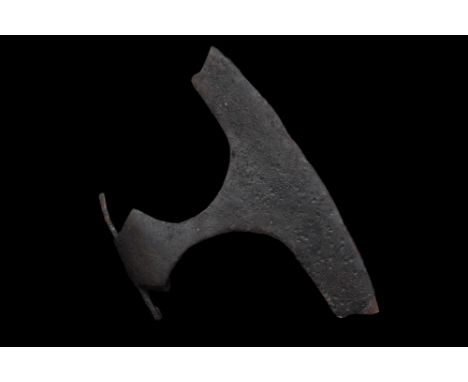 Ca. 1000-1100 AD. An iron axe head with a broad blade flaring to the curved cutting edge, with an eared socket with a round a