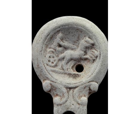 Ca. 100-200 AD. A ceramic lamp depicting a horse-drawn chariot. The filling hole on the discus and a wide spout adorned with 