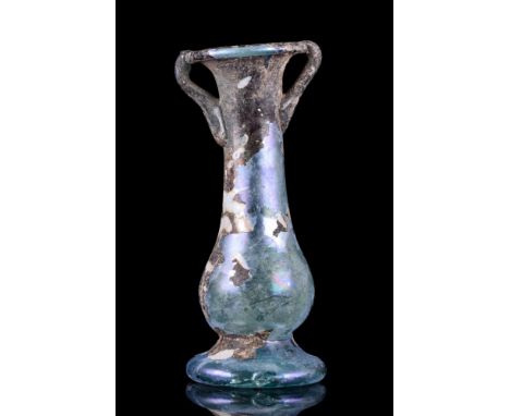 Ca. 4th–5th century AD. A glass unguentarium with a piriform body standing on an applied disc base featuring an everted mouth