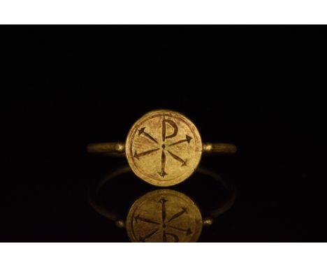 Ca. 300-400 AD. An elegant gold hoop with an attached circular plate bezel flanked by spherical baubles. The bezel features a
