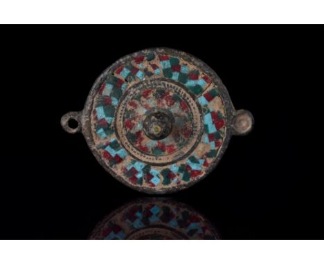 Ca. 300 AD. A beautiful flat circular broach featuring a central raised boss and a concentric ring decoration inlaid with col