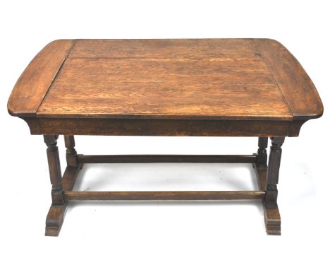 An early 20th century oak metamorphic dining table/sofa with ivorine label, raised on stretchered double legs, 74cm high x 13