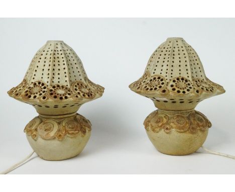 A pair of Bernard Rooke stoneware lamp bases, applied and impressed with flower heads and circles and pierced fluted shades, 