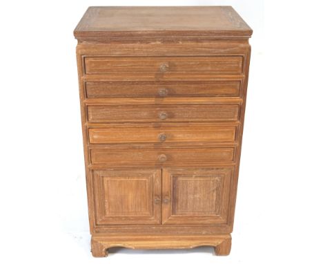 A limed Chinese chest, of rectangular form, the upper part set with five shallow drawers over two panelled doors, on a shaped