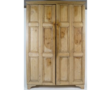 A pine two door cupboard, each door with six panels, opening to reveal four fixed shelves and panels to either side on bracke