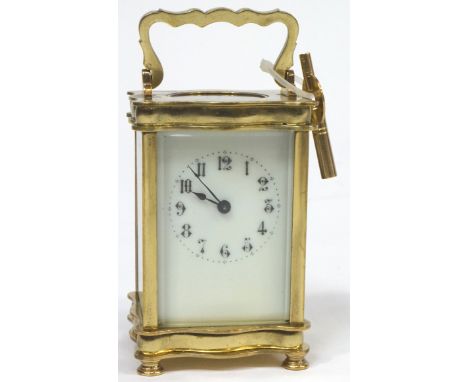 A French brass eight day carriage clock, of serpentine form, the white enamel dial with black numerals, the sides and top wit