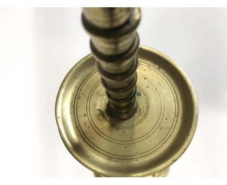 A late 18th/early 19th century brass candlestick with flared drip pan above a domed and shaped flared foot, 61.5cm high