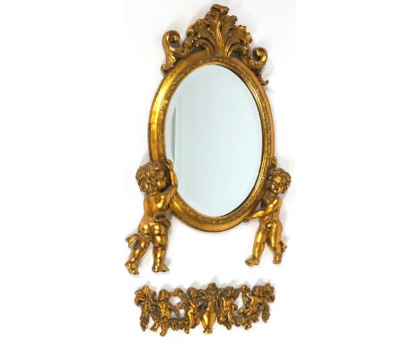A composition gilt mirror, formed with two draped putti supporting an oval plate under an acanthus cresting, 68cm high, with 