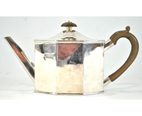 A silver teapot of flat panel octagonal form and domed cover, applied with a fruit wood handle and knop, London 1922, 26cm wi