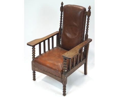 An early 20th century Art &amp; Crafts oak lounge chair, having stuffed and brown leather upholstery, the oak frame having bo