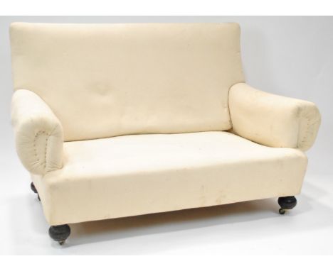 A calico upholstered sofa with two loose feather filled cushions on ebonised bun feet with ceramic casters, 130cm wide