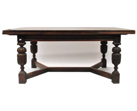 An oak extending dining table, of rectangular form, raised on acanthus carved  cup and cover legs, united by a double V form 