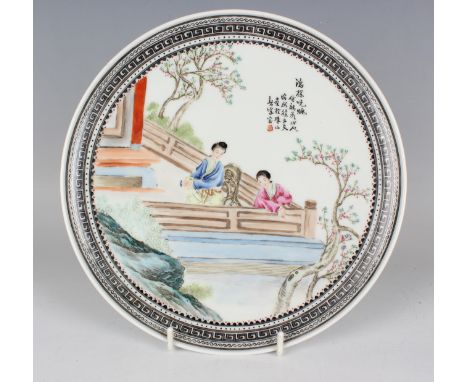 A Chinese famille rose porcelain plate, Republic period, painted with two maidens seated on a balcony between blossoming tree