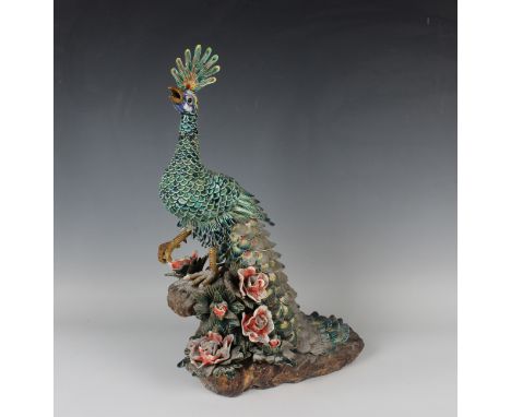 A Chinese pottery model of a peacock, 20th century, modelled on a flower encrusted rocky outcrop, the peacock with turquoise 